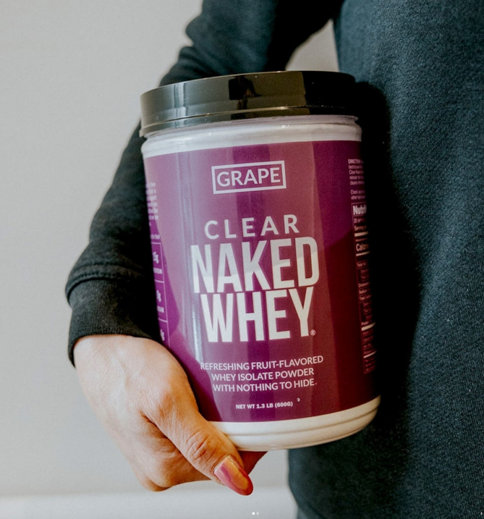 female holding a jar of naked clear whey protein