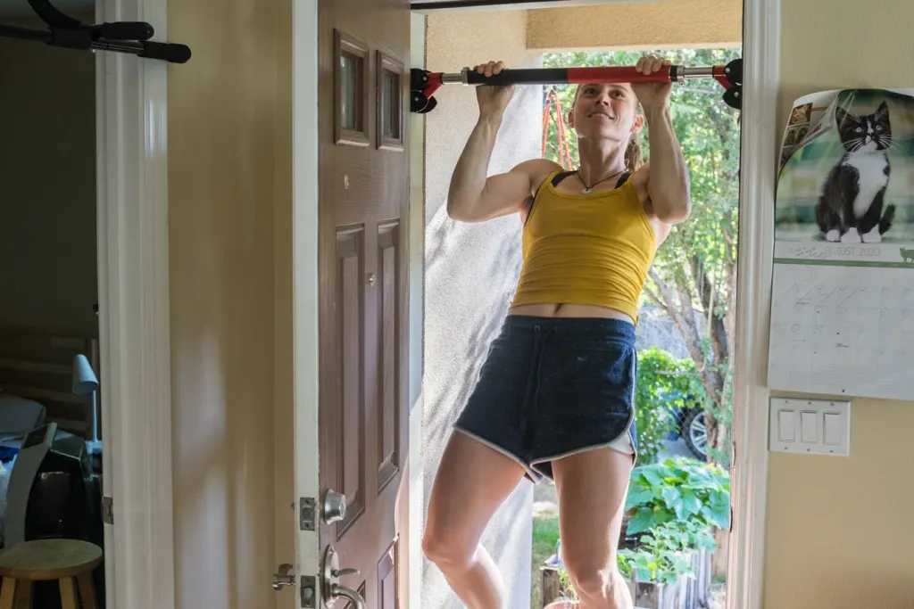 Women Using Door Pull Up Bar in Home