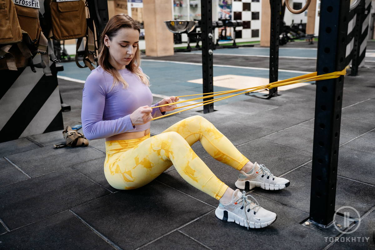 athlete woman doing exercise with resistance band in gym