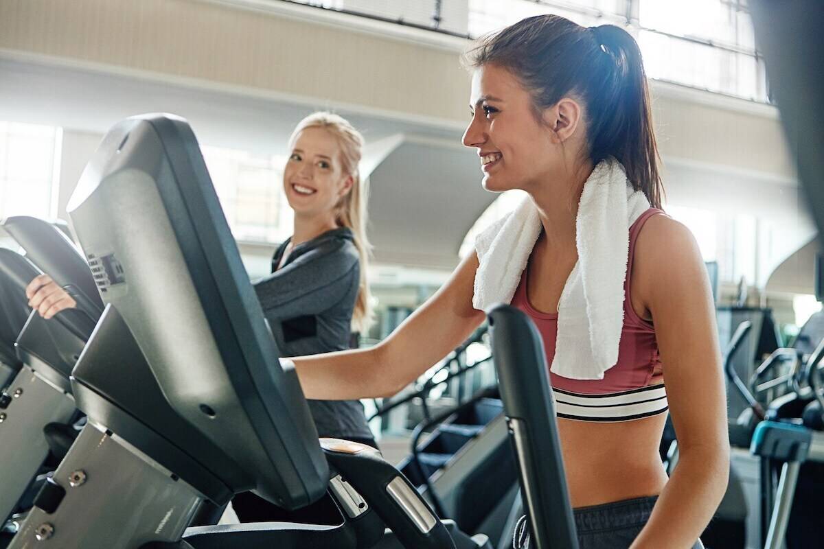 Woman athlete with towel training on stairmaster machine