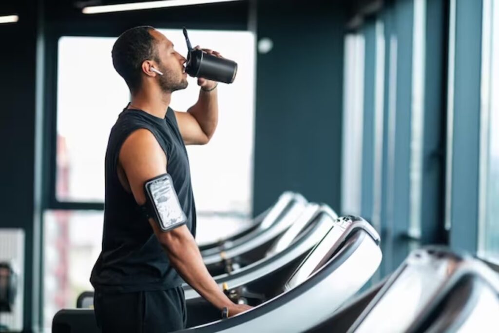 man drinking water on treadmill