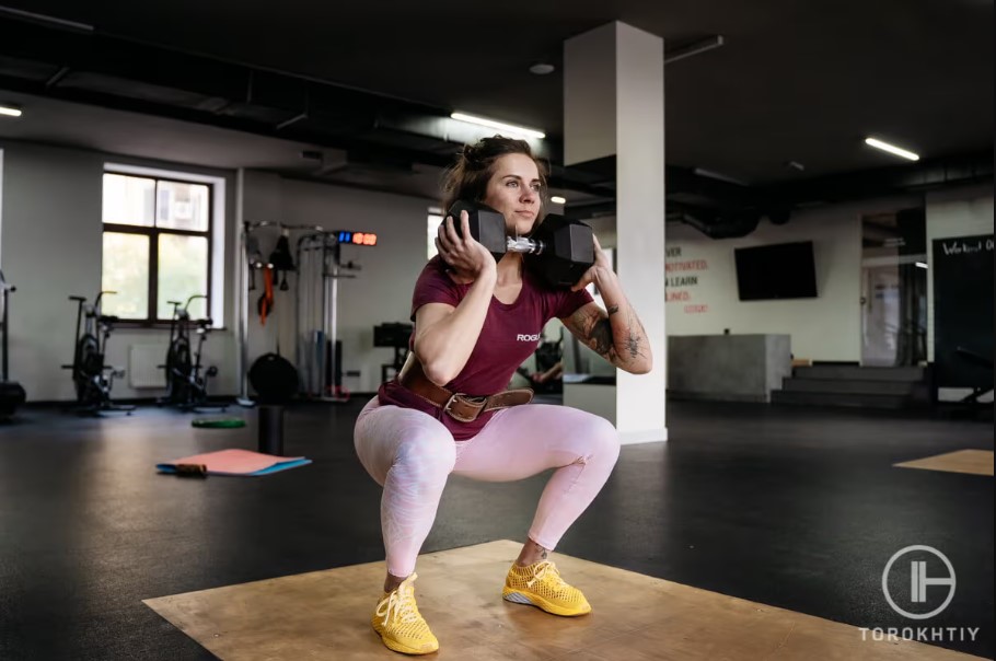 woman doing squats with dumbbell