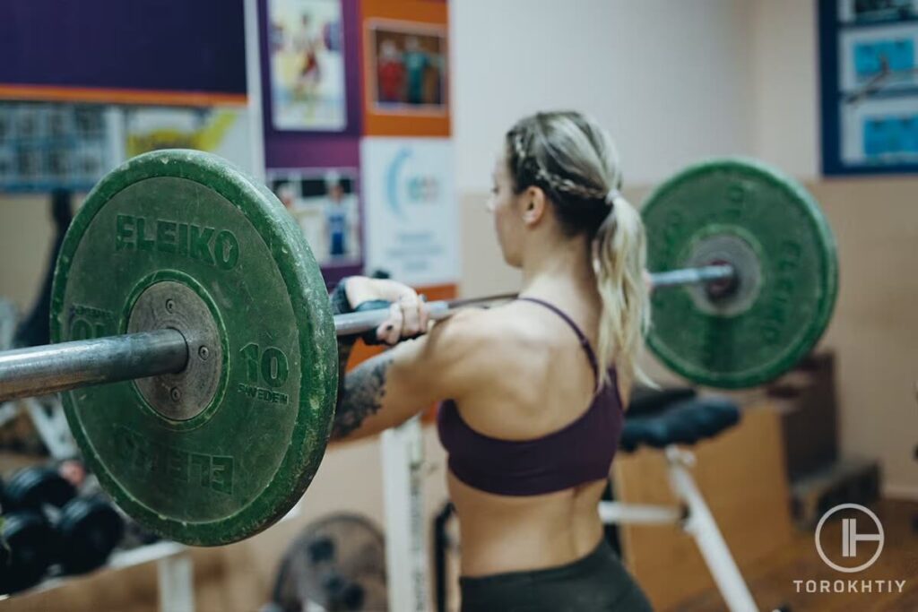 female athlete training with barbell in gym