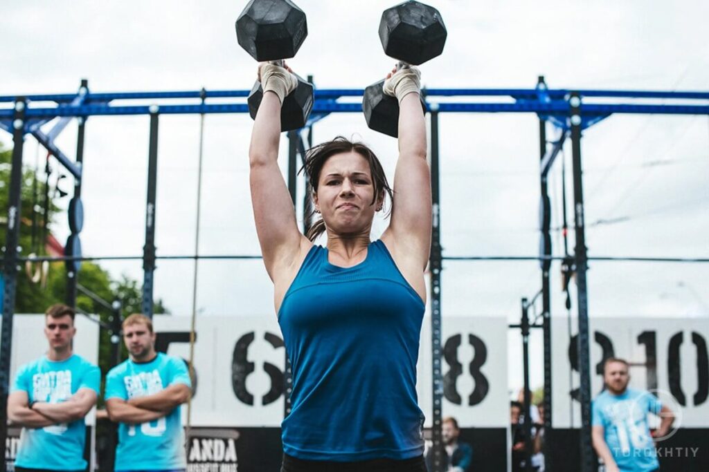 female athlete in blue training with dumbbells