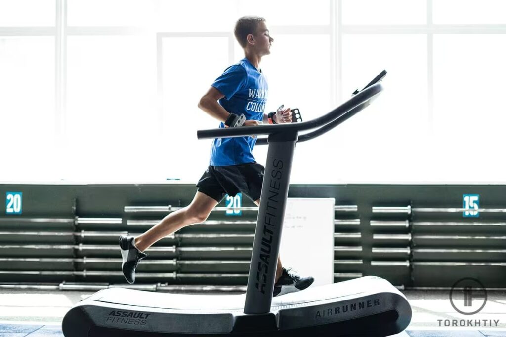 young athlete in blue shirt running on treadmill