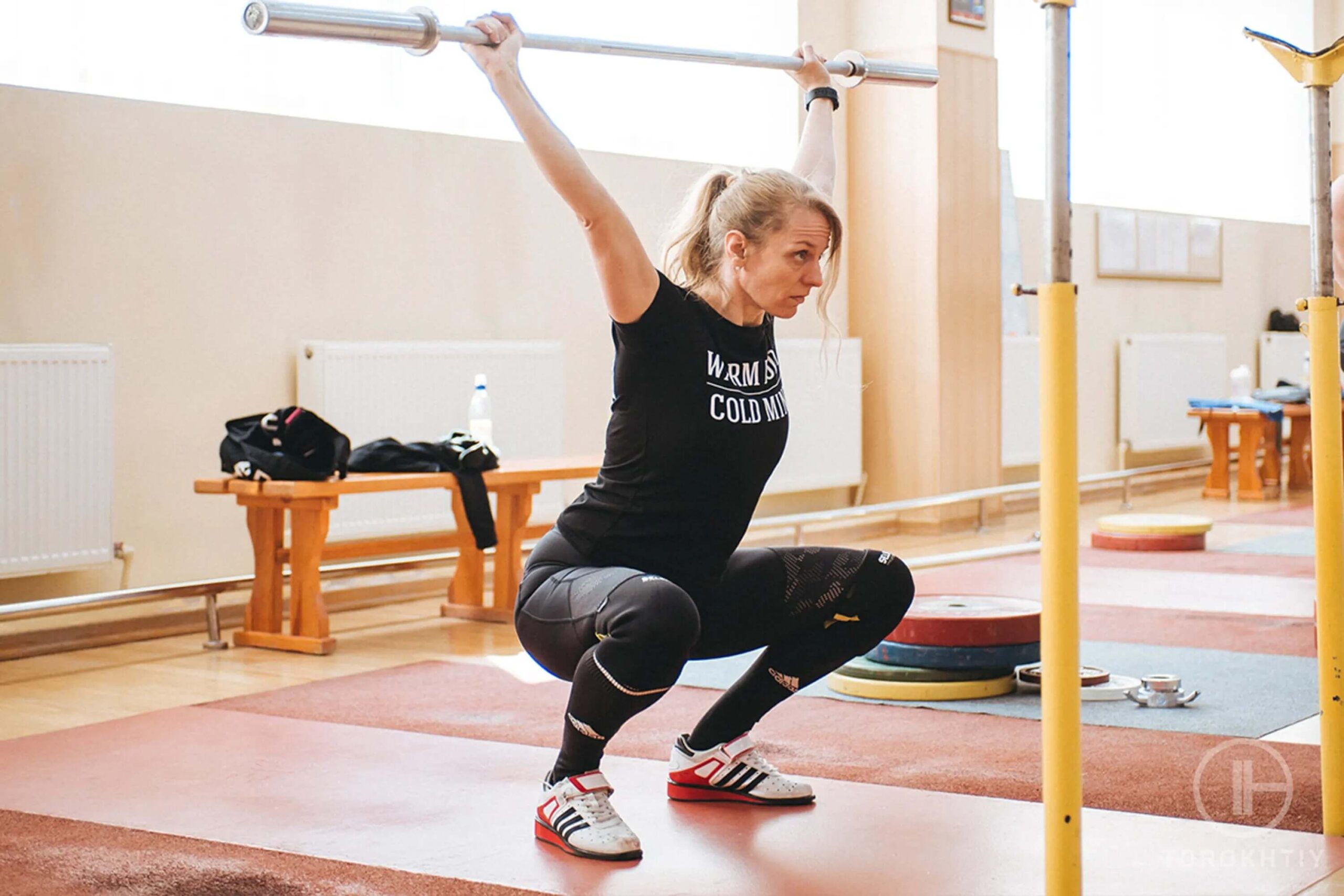 athlete woman holds barbell over head