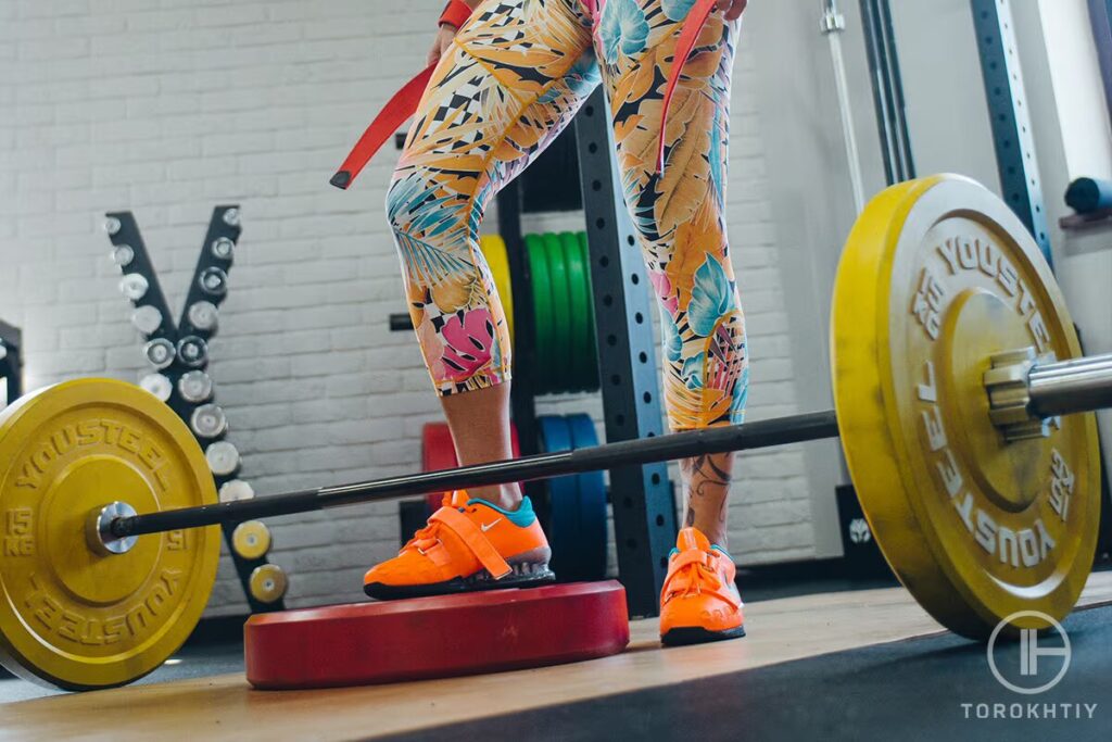 barbell and legs of athlete woman