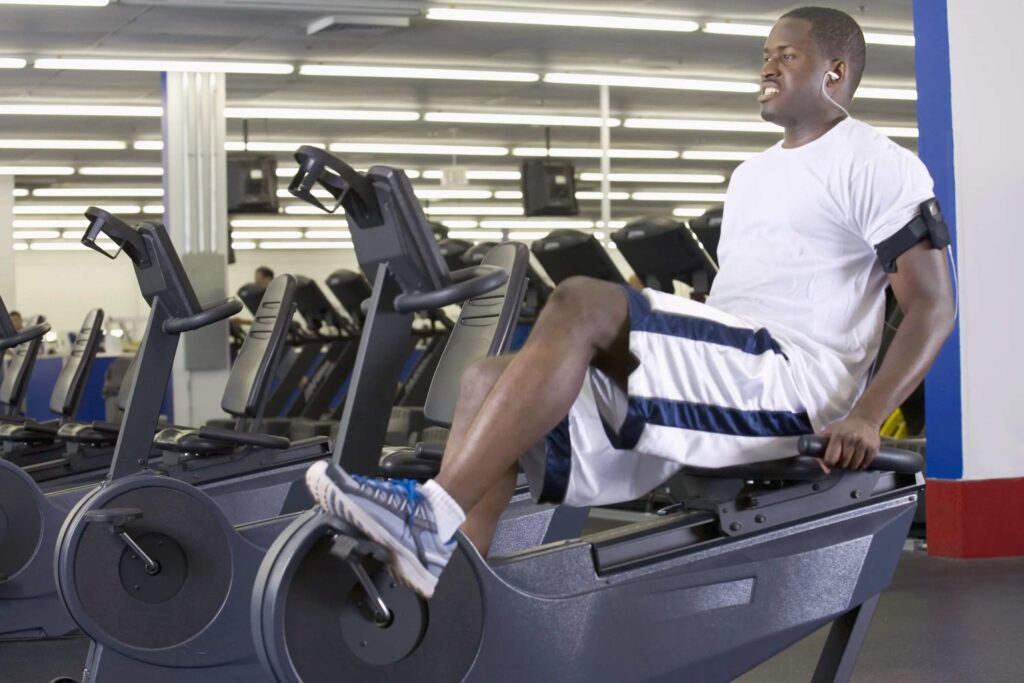 man exercises on recumbent bike in gym
