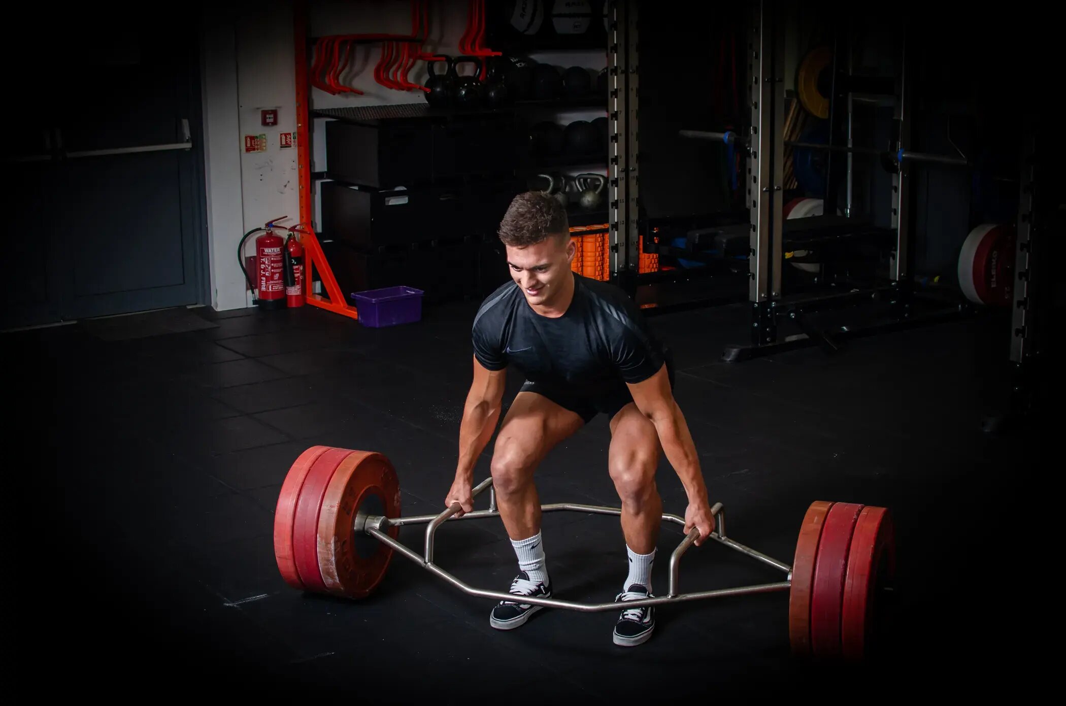 athlete man lifts trap bar in gym