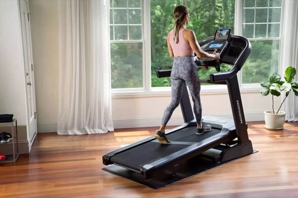 woman exercises on treadmill at home by window