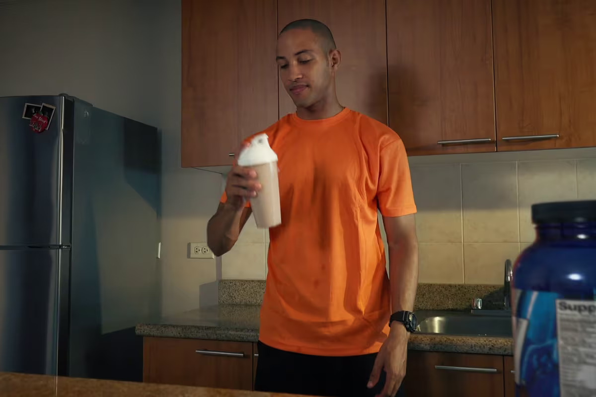 athlete man hold protein milk shakw in his kitchen