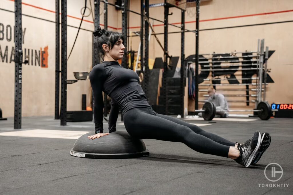 athlete woman doing exercise on bosu ball in gym