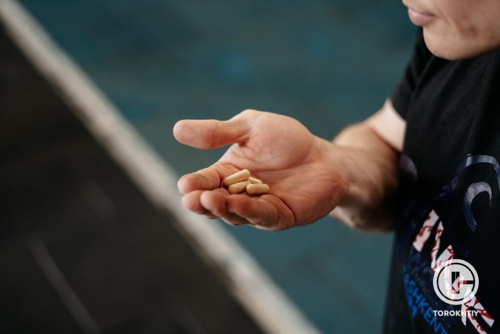 athlete holds supplements in capsules