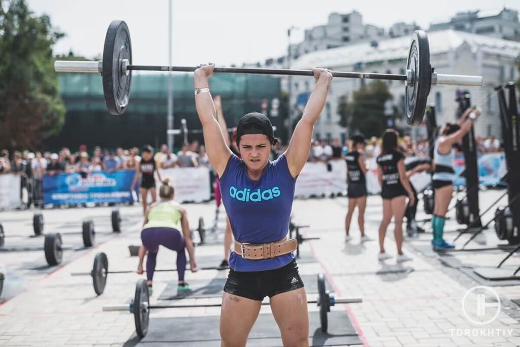 female athlete training with barbell outside