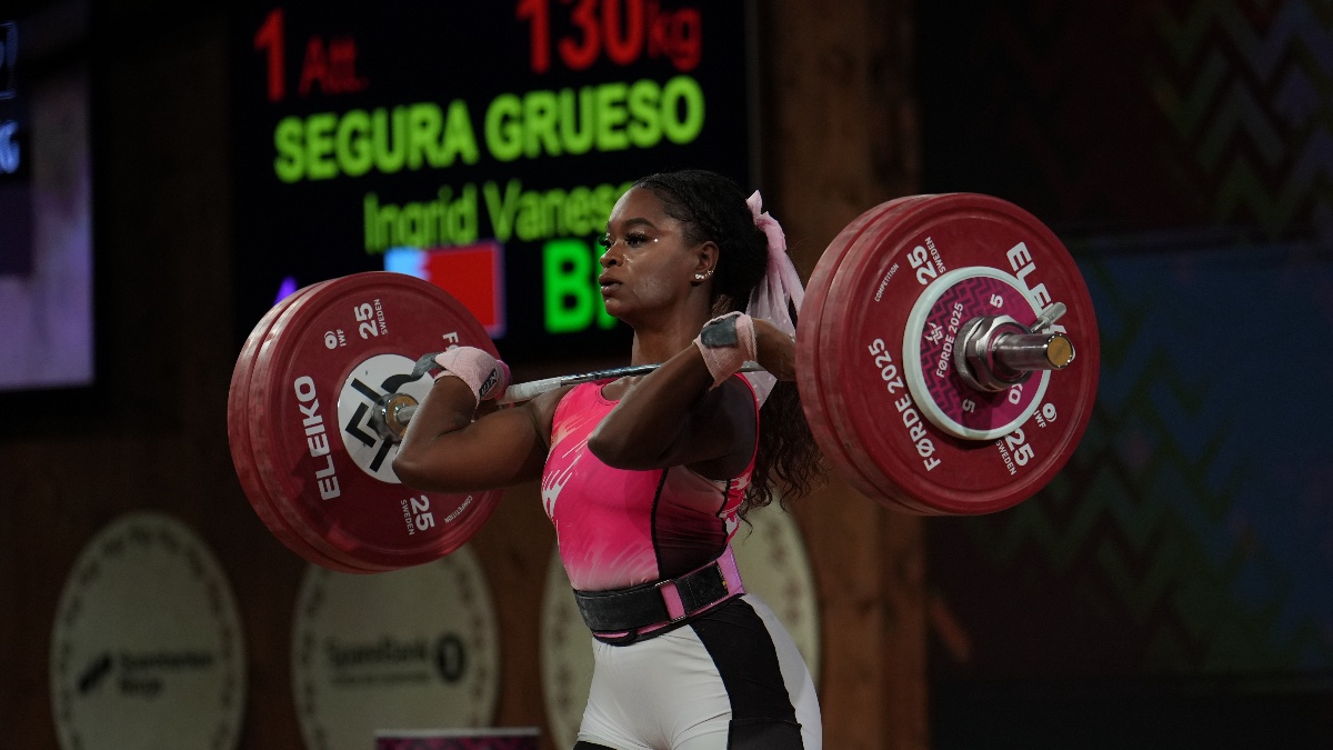 Weightlifter Segura Grueso Ingrid Vanesa in pink holds a 130 kg barbell at shoulder height; scoreboard shows her name (Torokhtiy Weightlifting)
